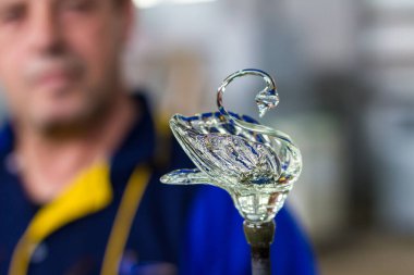 Beloslav / Bulgaristan - 5 Mayıs 2019: Cam üfleyici güzel bir cam parçası oluşturuyor. Bir cam ustası yanıyor ve bir sanat eserini üflüyor.. 