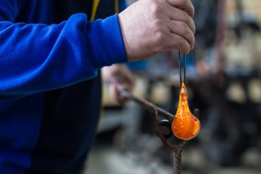 Cam üfleyici güzel bir cam parçası oluşturuyor. Bir cam ustası yanıyor ve bir sanat eserini üflüyor.. 