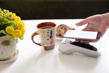 Kafedeki cep telefonuyla yapılan bağlantısız ödemeler. Kahve dükkanındaki müşteriler terminale ödeme yapıyor..