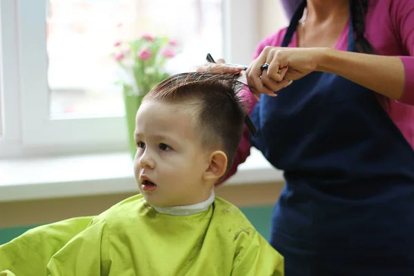 Перукар робить зачіску маленьким хлопчиком, крупним планом . — стокове фото
