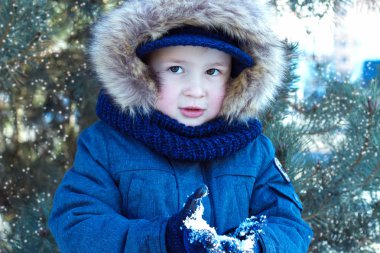 Küçük oğlan mavi ceketli düşen kar elinde görünüyor.