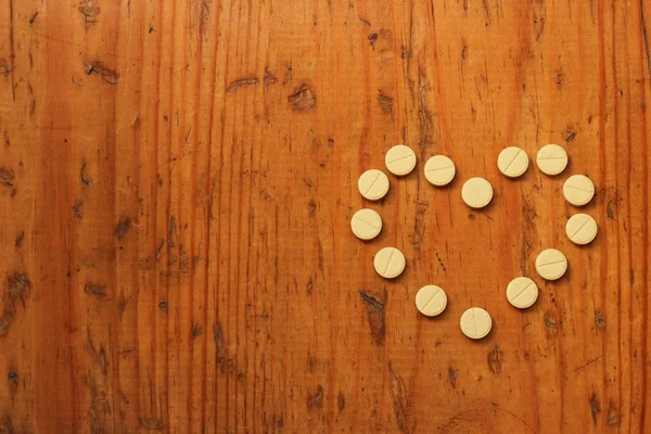 Coração - de pastilhas em um contexto de madeira, o conceito de droga — Fotografia de Stock