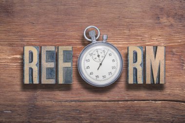 Eski verniklenmiş ahşap yüzeyde kronometre ile birleştirilmiş reform kelimesi