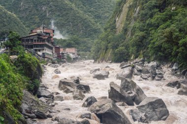 Peru 'daki Urubamba nehrinin güçlü dağ deresinin üzerindeki Aguas Calientes kasabasına bakın.