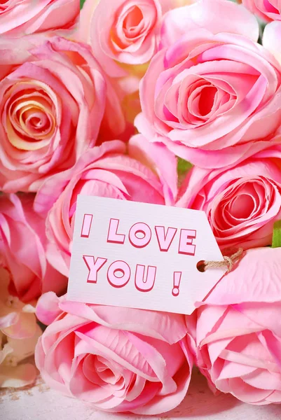 Roze rozen en papier tag met liefde tekst — Stockfoto