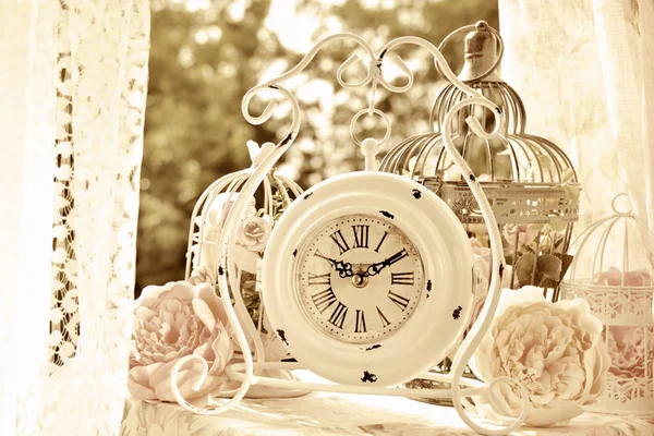 Reloj blanco de estilo vintage y jaulas para pájaros con flores en sepia —  Fotos de Stock