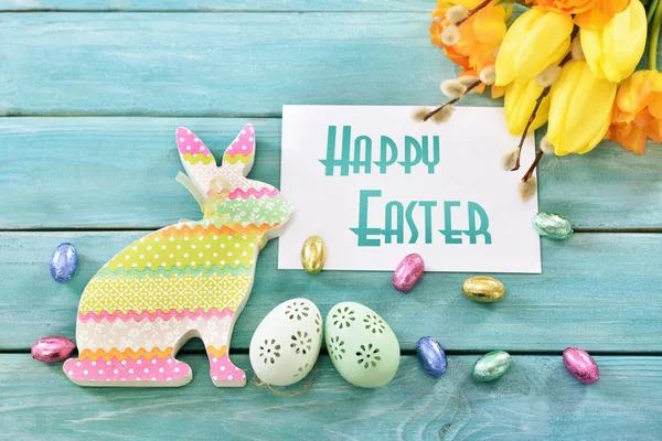 Tarjeta de felicitación de Pascua con conejo colorido, huevos y tulipanes — Foto de Stock