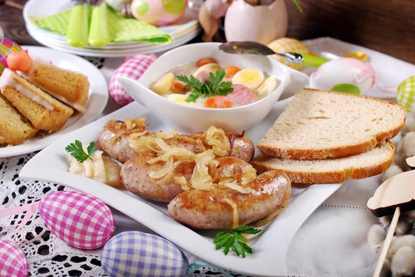 伝統的なイースターホワイトソーセージに玉ねぎと白ボルシチと野菜と卵を盛り付けたお祝いのテーブル — ストック写真