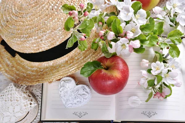 春は昔の本の上にりんごや花の枝やわらの帽子とロマンチックなスタイルでまだ生活 — ストック写真