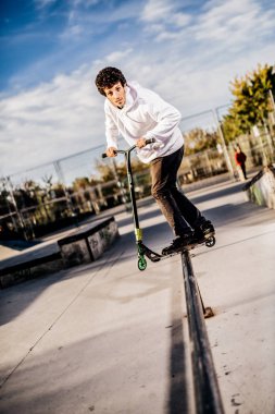 Genç adam bir eziyet Skatepark üzerinde yapma scooter ile 