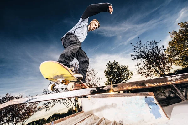 Jovem patinador fazendo uma moagem no Skatepark durante o pôr do sol — Fotografia de Stock