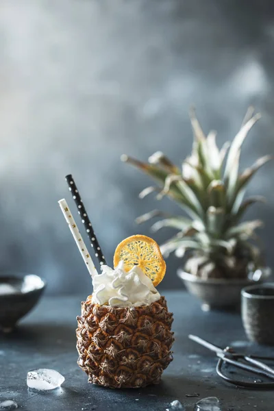 pineapple with drink, creamy top, orange slice and drinking straws