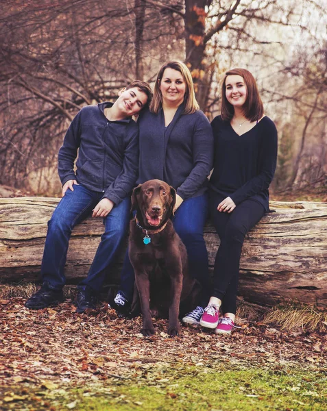 Eine Familie sitzt mit ihrem Hund in einem Park — Stockfoto