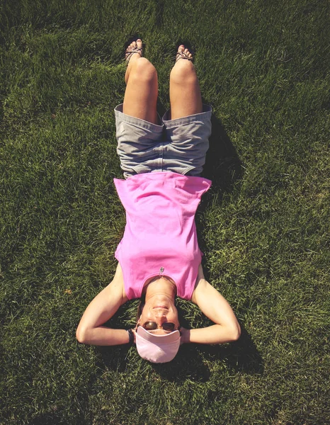 Симпатичная девушка, лежащая в зеленой траве — стоковое фото