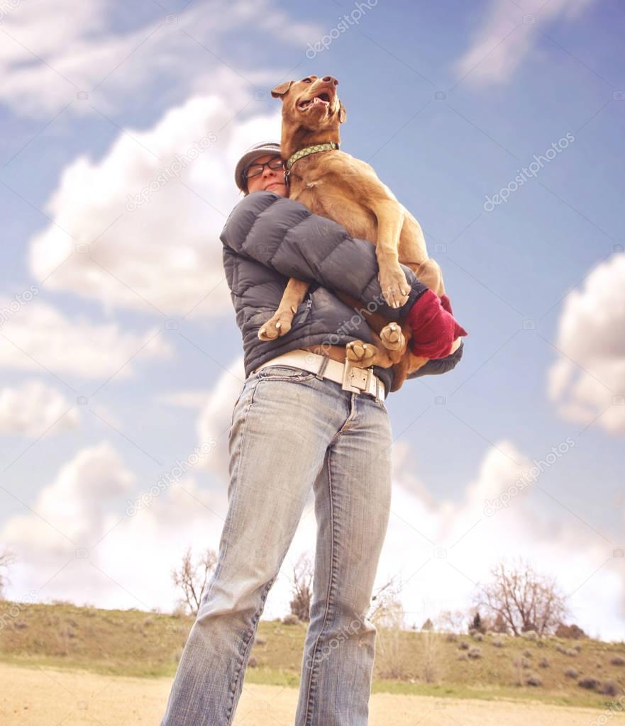 a girl holding her big dog in her arms 