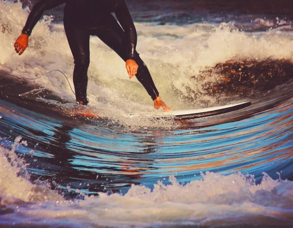 Um surfista montando uma onda em um terno molhado completo — Fotografia de Stock