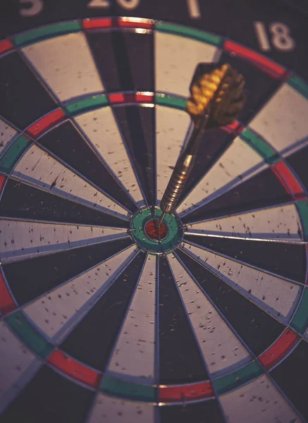 a dark moody image of a dartboard with a dart in the center bull