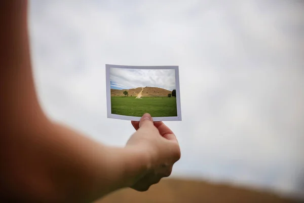 Ein junges Mädchen hält ein Sofortbild vor einer Landschaft. — Stockfoto