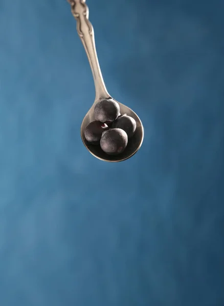An antique metal baby spoon with ripe blue berries on it over a — Stock Photo, Image