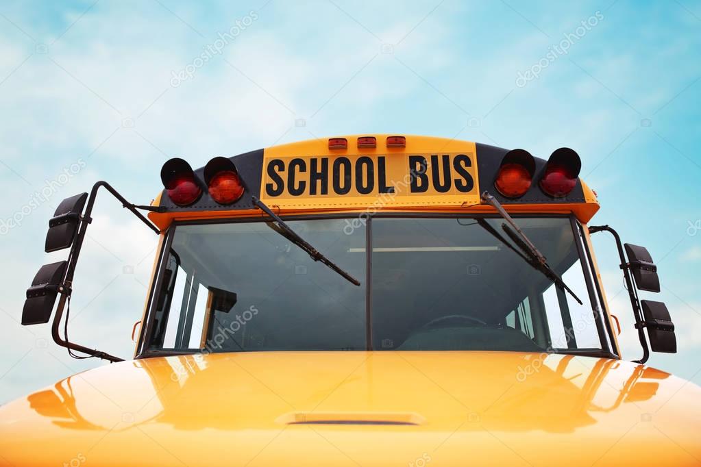 wide angle front view of a bright yellow orange school bus on a