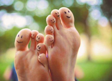 smiley faces on a pair of feet on all ten toes in a park on a hot summer day  clipart