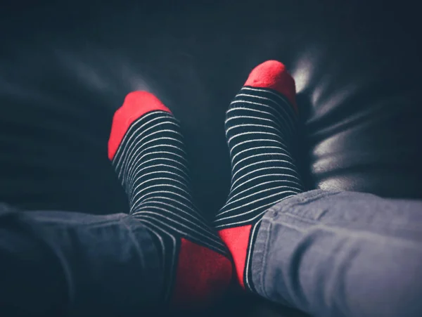 Унылое фото черно-красных полосатых носков на диване с матовым ретро-винтажным фильтром инастаграммы — стоковое фото
