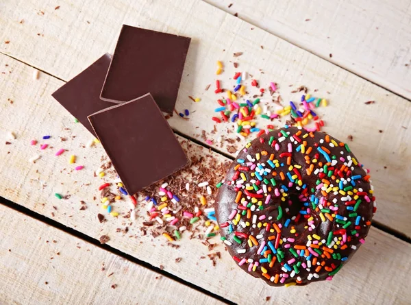 Estúdio overhead tiro de um donut com polvilhas em um fundo de madeira conceito de comida não saudável — Fotografia de Stock