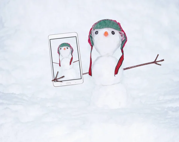 Foto auténtica de un muñeco de nieve pequeño con una tapa roja vintage retro y una nariz de zanahoria en un día frío de invierno — Foto de Stock