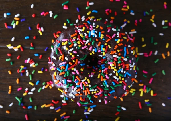 Estúdio overhead tiro de um donut com polvilhas em um fundo de madeira conceito de comida não saudável — Fotografia de Stock