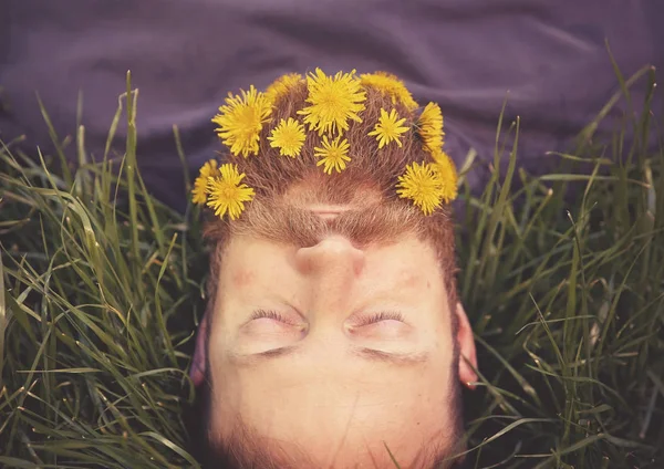 Hipster endormi couché dans l'herbe haute avec des pissenlits dans sa barbe épique faire une sieste tonique avec un filtre instagram vintage rétro — Photo