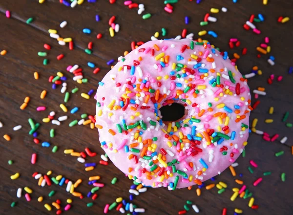 Estúdio overhead tiro de um donut com polvilhas em um fundo de madeira conceito de comida não saudável — Fotografia de Stock