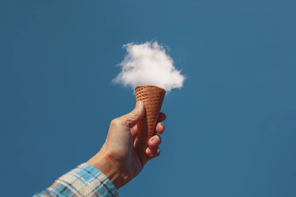 Hand holding a sugar cone in front of a fluffy white cloud toned with a retro vintage instagram filter — Stock Photo, Image