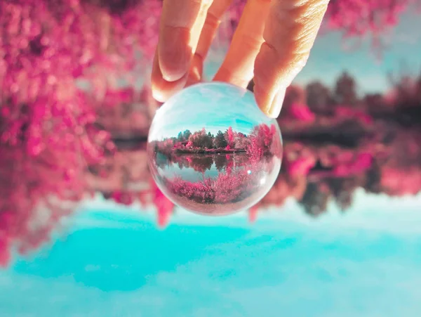 上下手拿着一个水晶照片球在公园与池塘和树木色调与复古复古 instagram 过滤器 — 图库照片