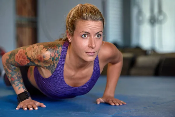 Mulher com tatuagens fazendo push up exercício — Fotografia de Stock