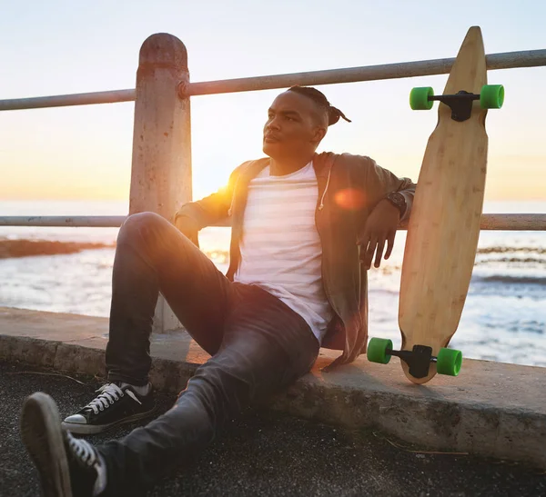 Uomo africano seduto con longboard — Foto Stock