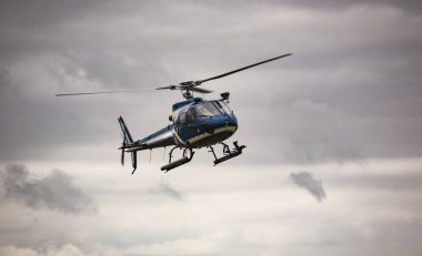 Mavi helikopter gri gökyüzünde uçuyor