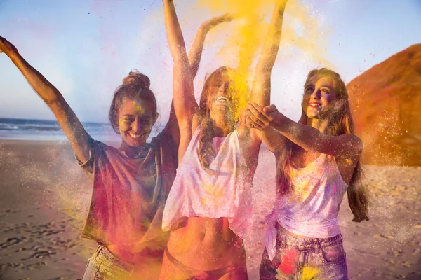 Três meninas com as mãos para cima cheias de pó colorido — Fotografia de Stock