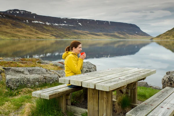 Touristin ruht sich am Tisch am See aus — Stockfoto