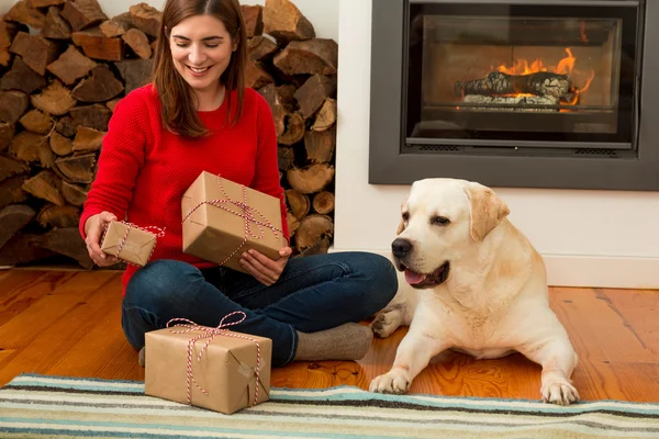 Vrouw zittend op de vloer met hond en geschenken — Stockfoto