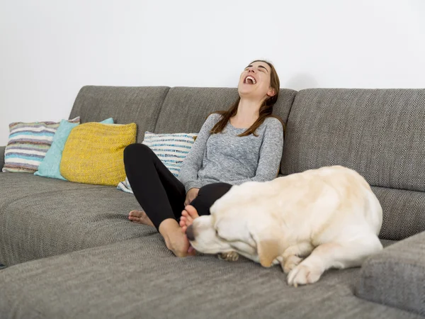 Kvinna sitter på soffan med hund — Stockfoto