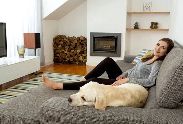 Woman sitting on sofa with dog — Stock Photo, Image
