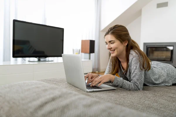 Kobieta pracuje na laptopie, leżąc na kanapie — Zdjęcie stockowe