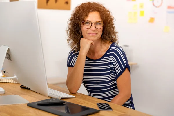 Smiling businesswoman sitting at office — Stock Photo, Image
