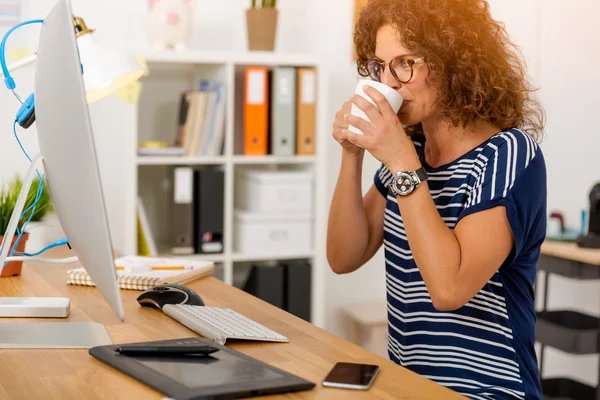 Geschäftsfrau sitzt und trinkt Kaffee im Büro — Stockfoto