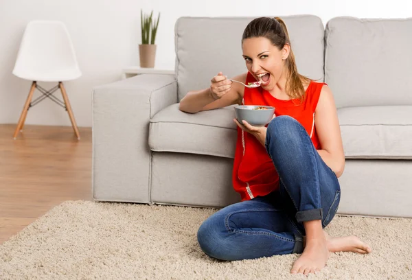 Woman in red singlet sitting on carpet — Stock Photo, Image