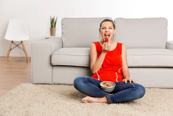 Woman in red singlet sitting on carpet — Stock Photo, Image