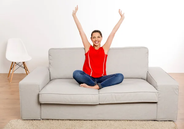 Женщина в красном сингле, сидящая на диване — стоковое фото