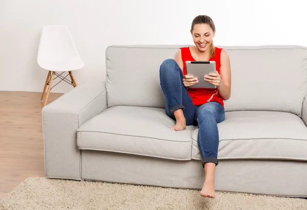 Mujer en singlet rojo sentado en el sofá — Foto de Stock