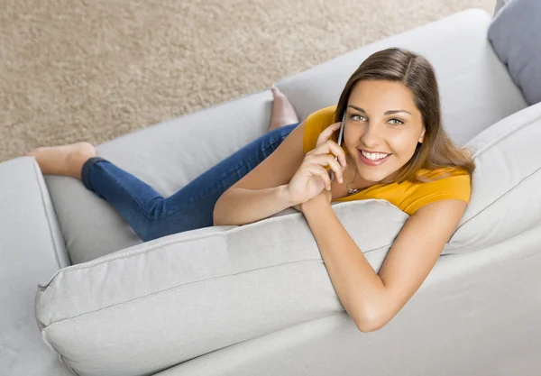 Жінка в жовтій футболці сидить на дивані — стокове фото