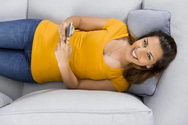 Жінка в жовтій футболці лежить на дивані — стокове фото